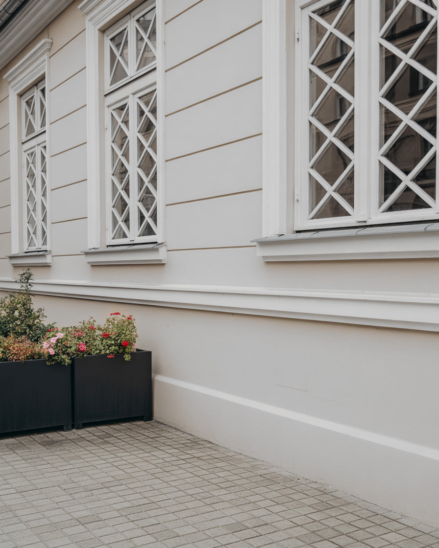 Elegant cream-toned building façade with patterned windows and modern outdoor planters