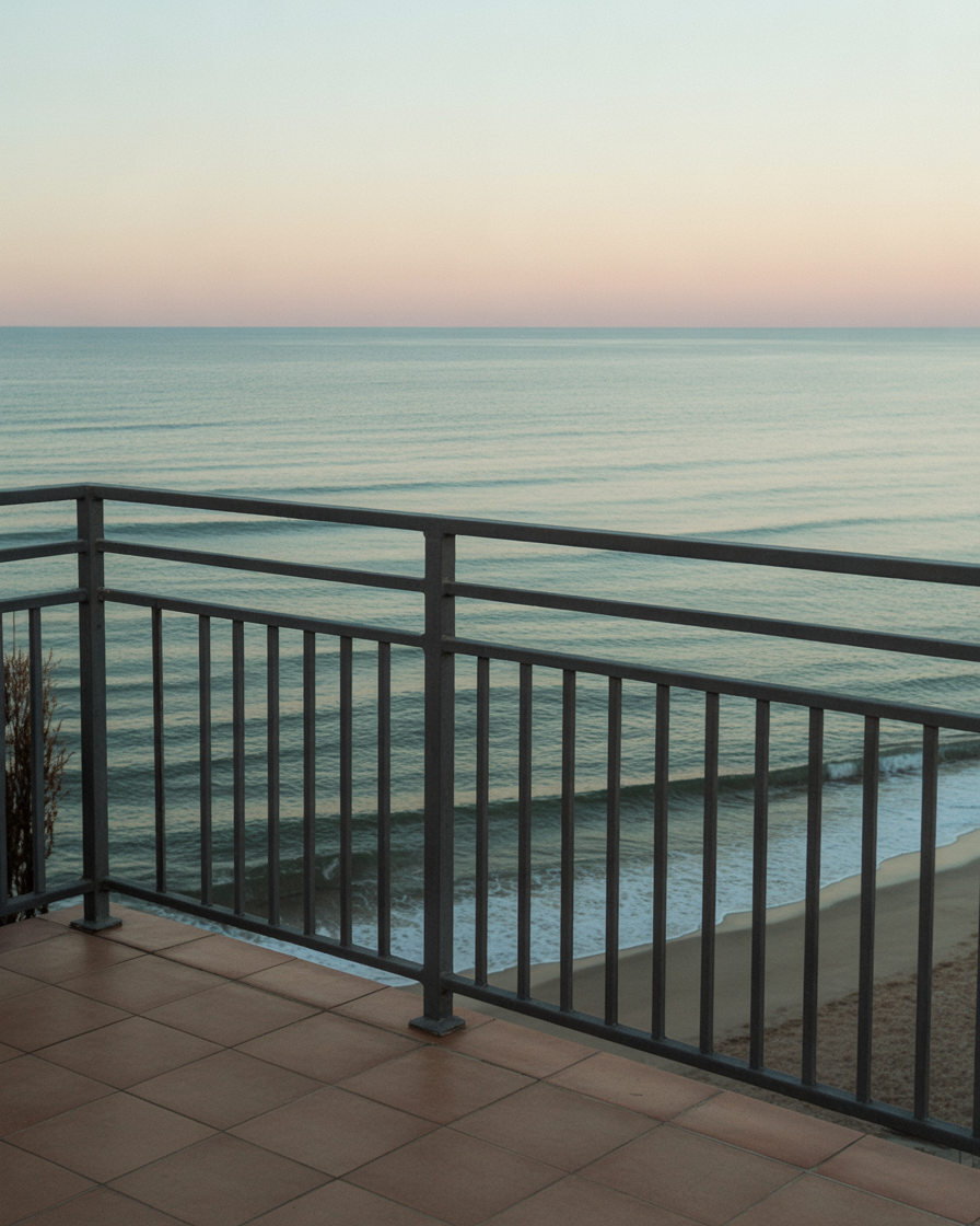 Peaceful seaside balcony overlooking gentle ocean waves at pastel sunset