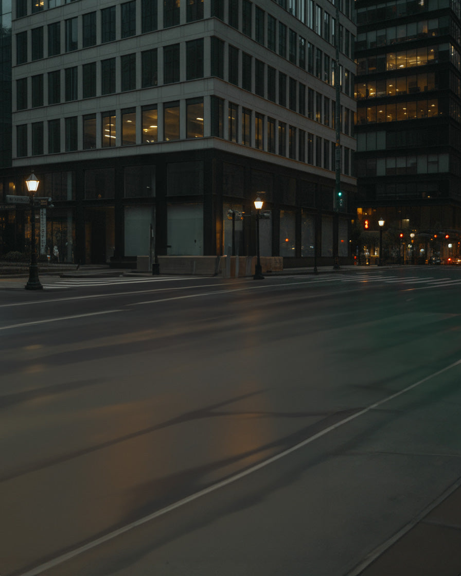 Moody downtown street corner with glowing lampposts and reflective nighttime pavement