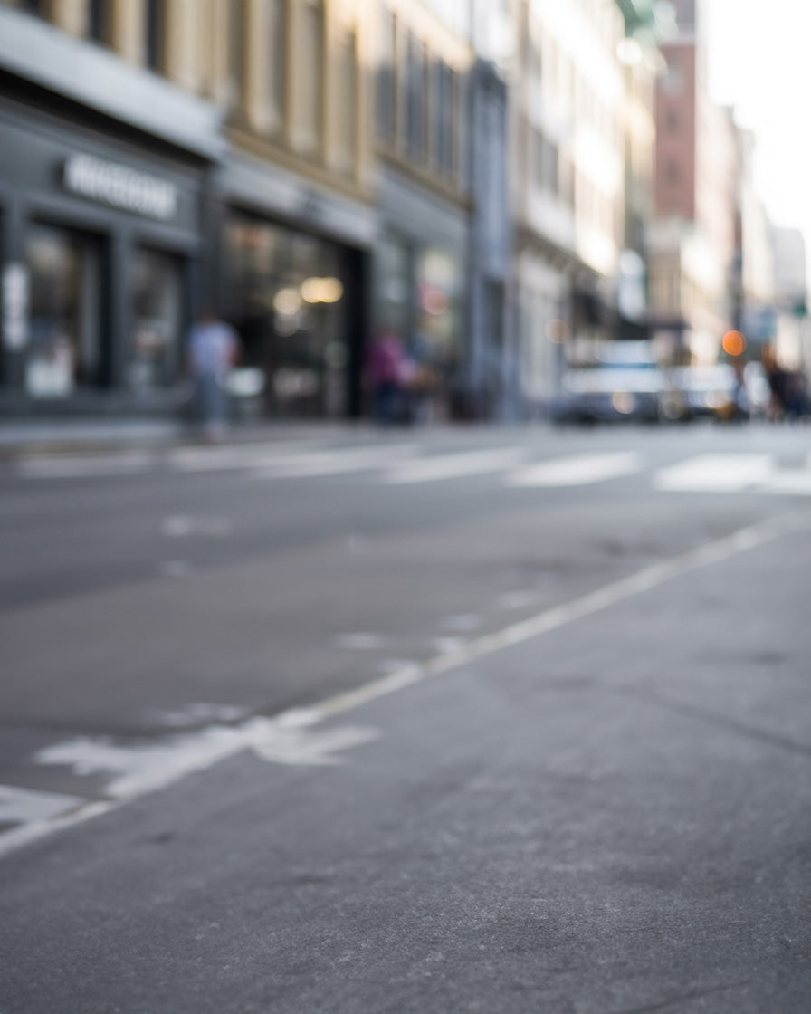 Soft urban street with blurred storefronts and muted daylight