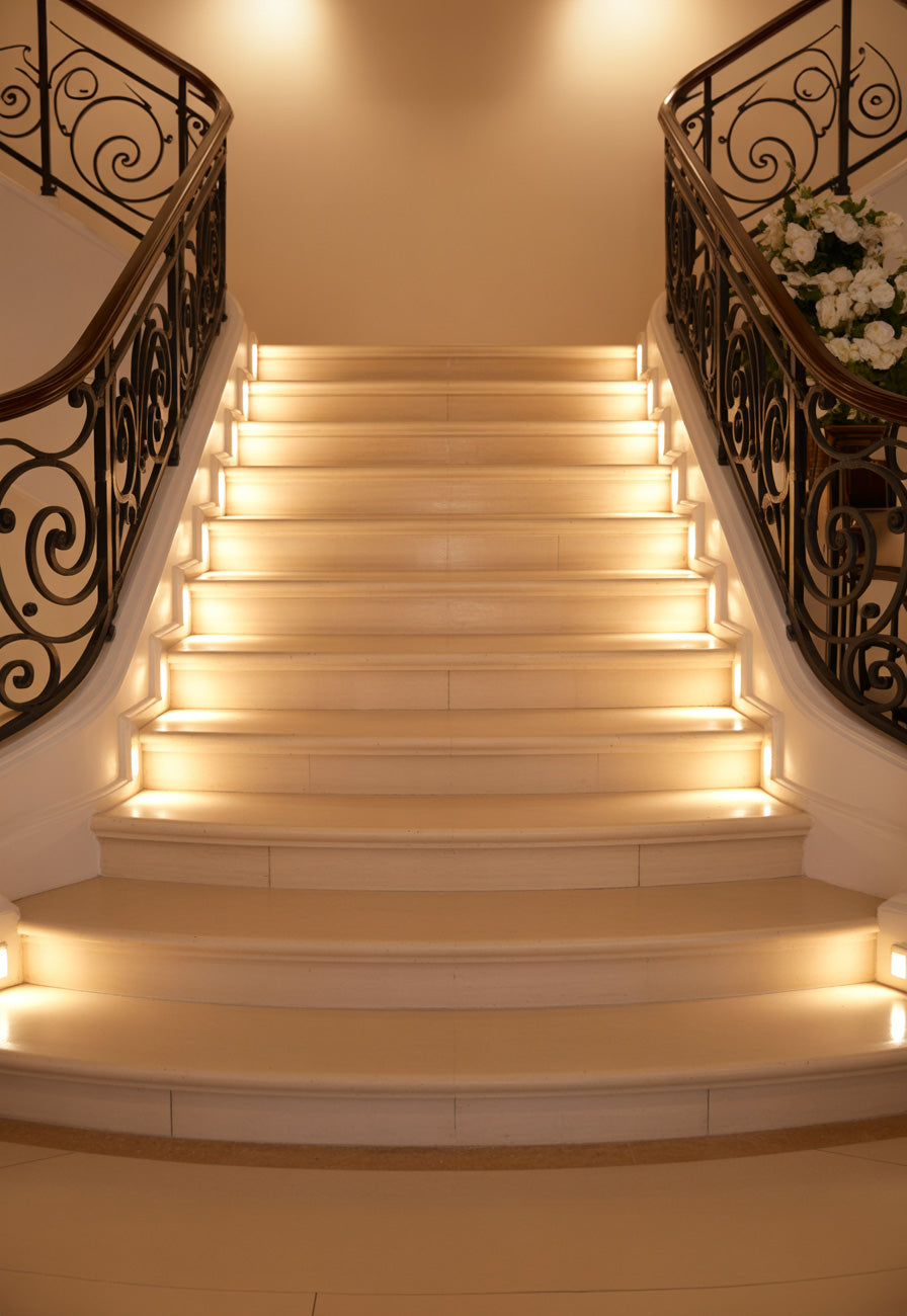 Warmly lit grand staircase with ornate railings in elegant indoor setting