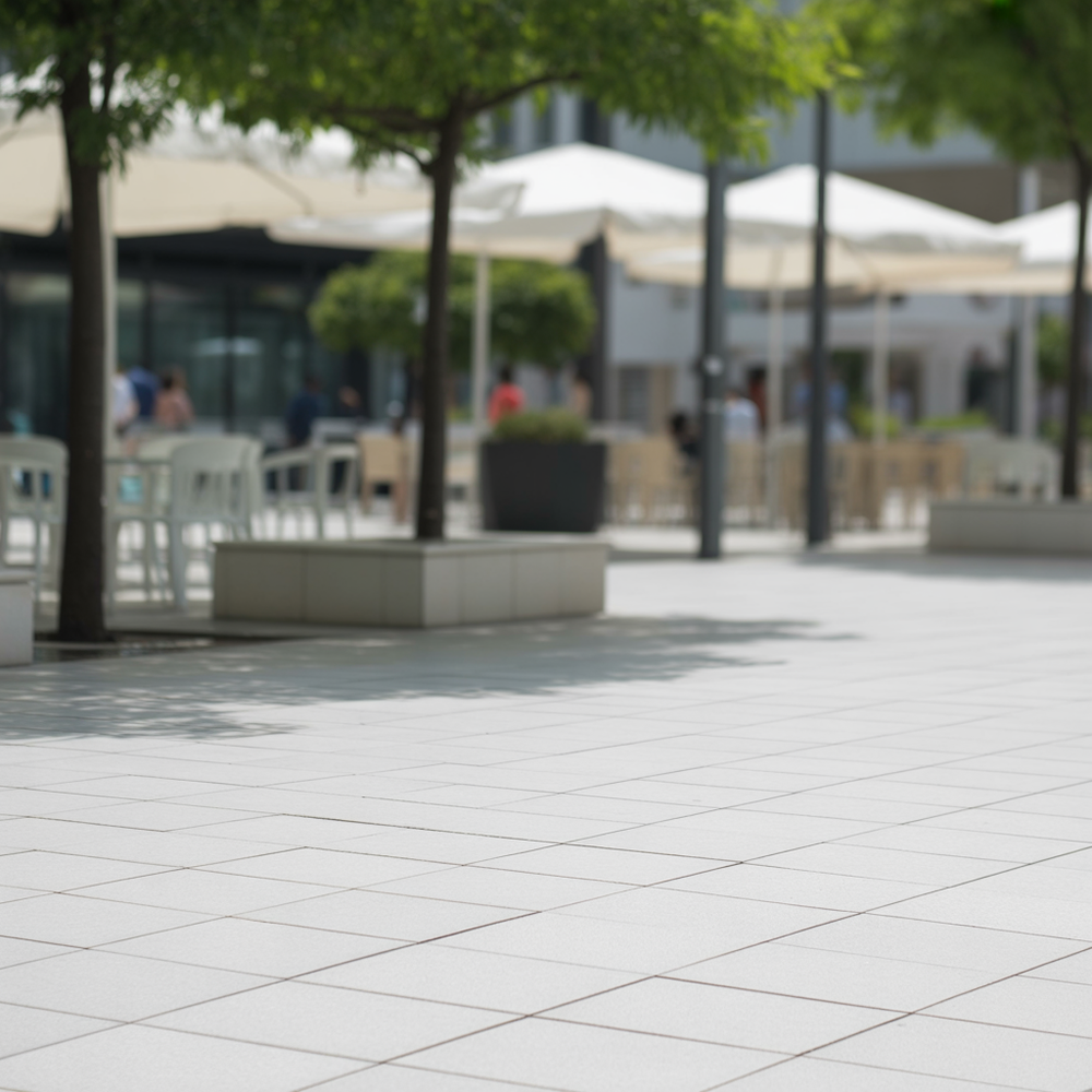 Open plaza with trees, umbrellas, and sunlit stone tiles
