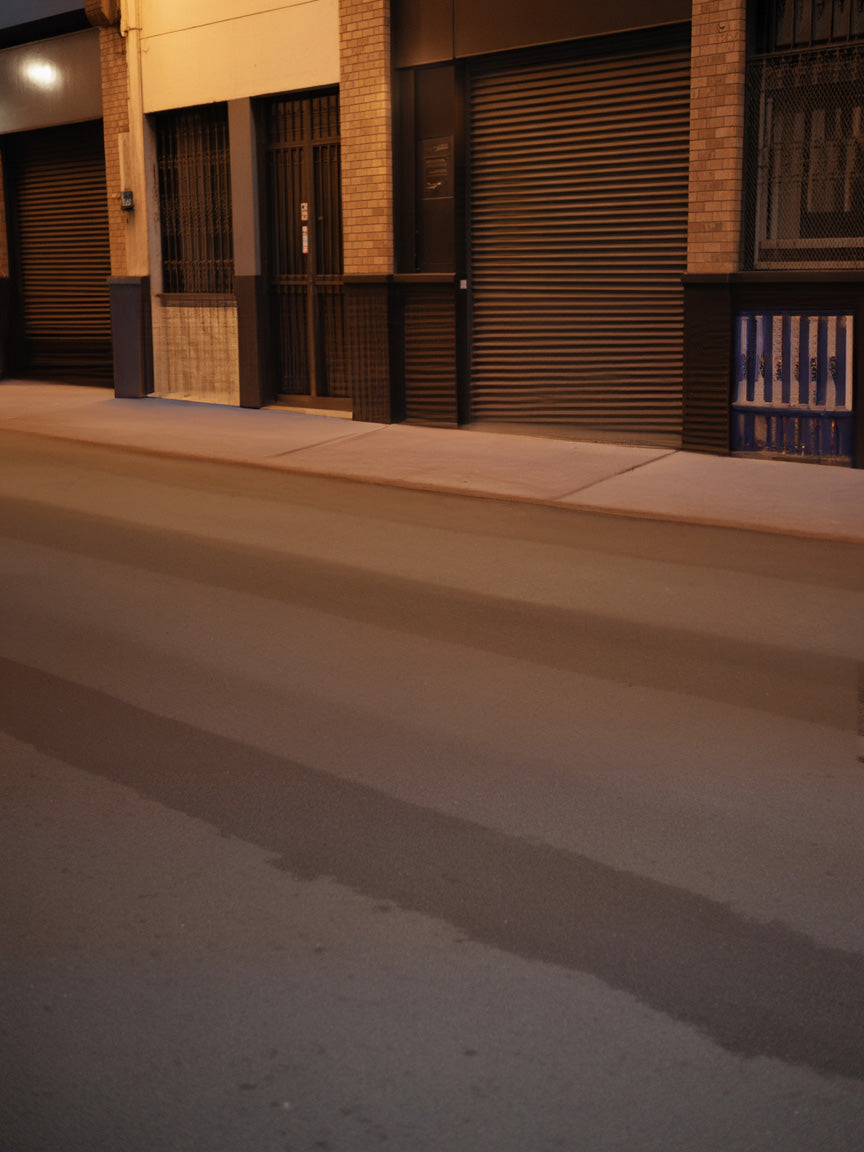 Quiet urban street at night with closed shutters and warm lighting