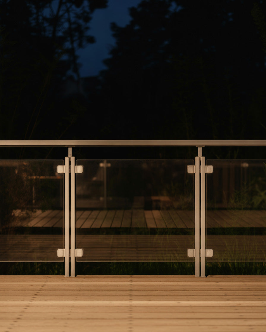 Modern outdoor deck with glass railing illuminated softly at night