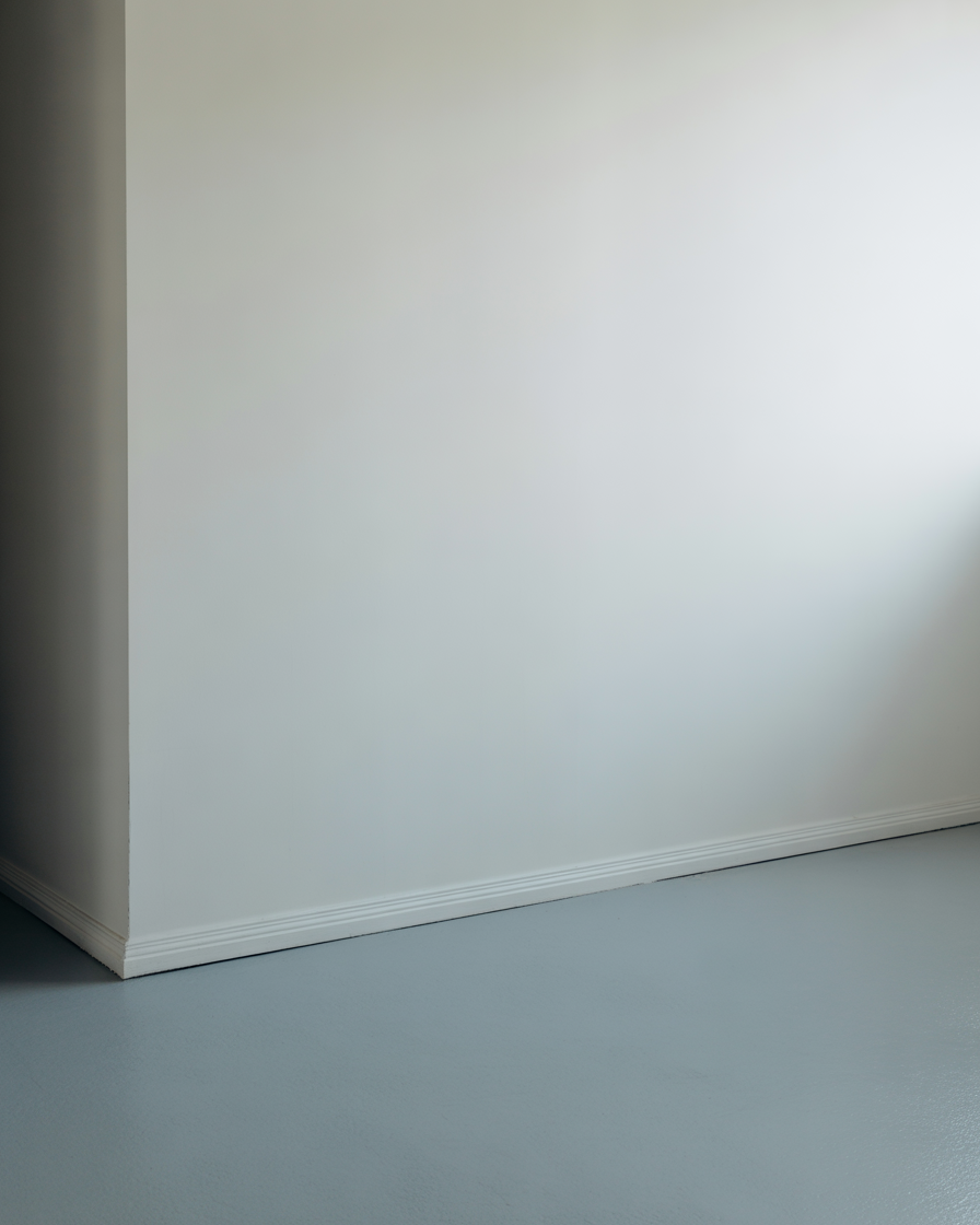 Indoor studio corner with smooth white wall and cool gray floor