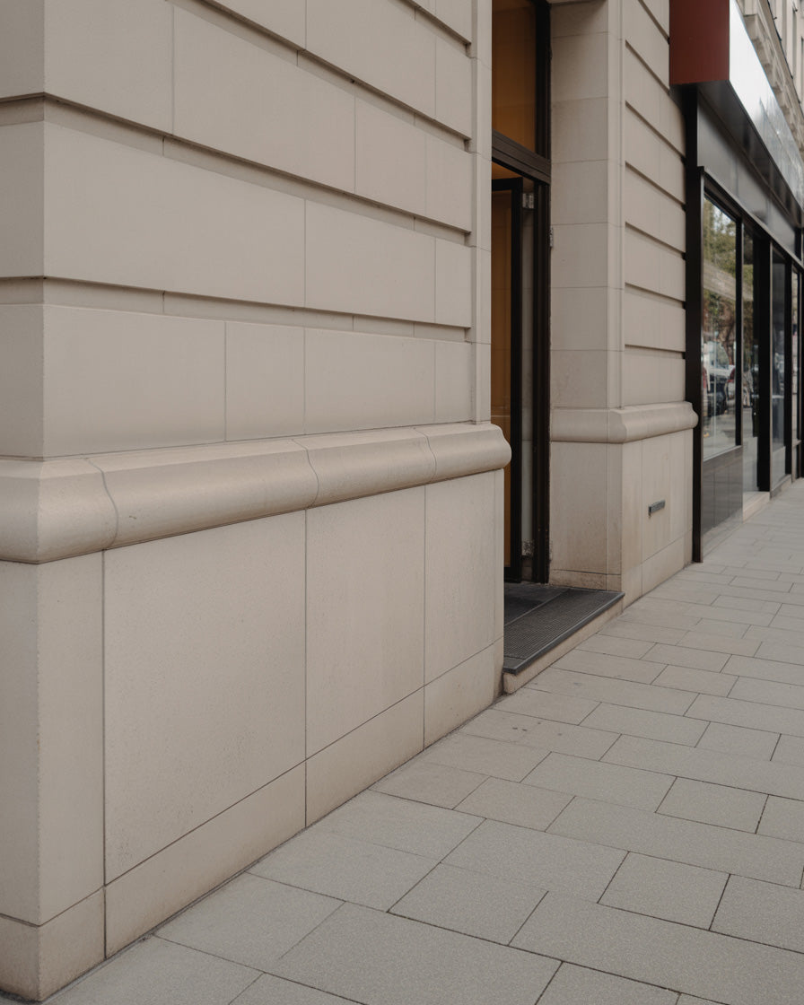 Stone building facade with tiled sidewalk in urban commercial area