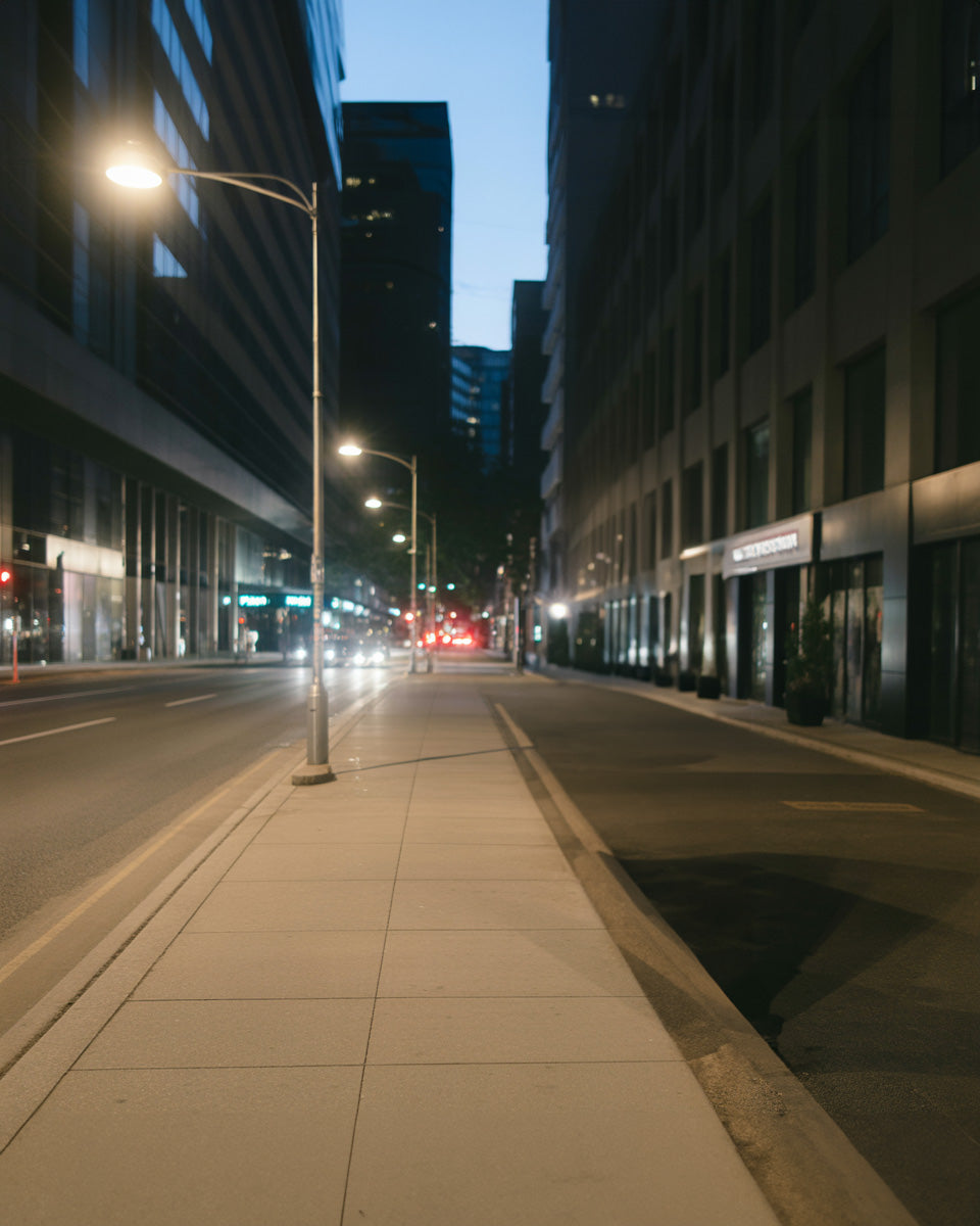 Quiet night city street with soft streetlights and empty sidewalk