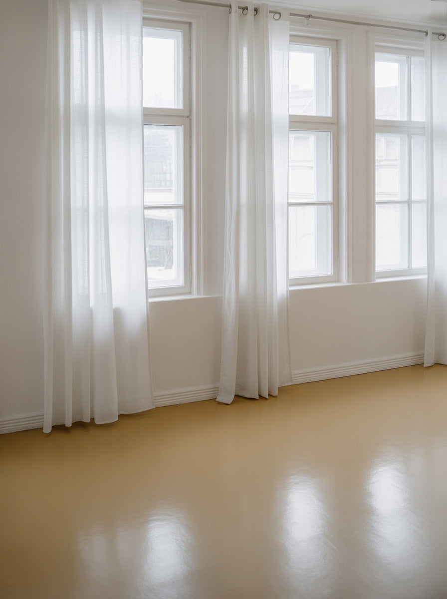 Soft natural light filled room with sheer curtains and neutral floors