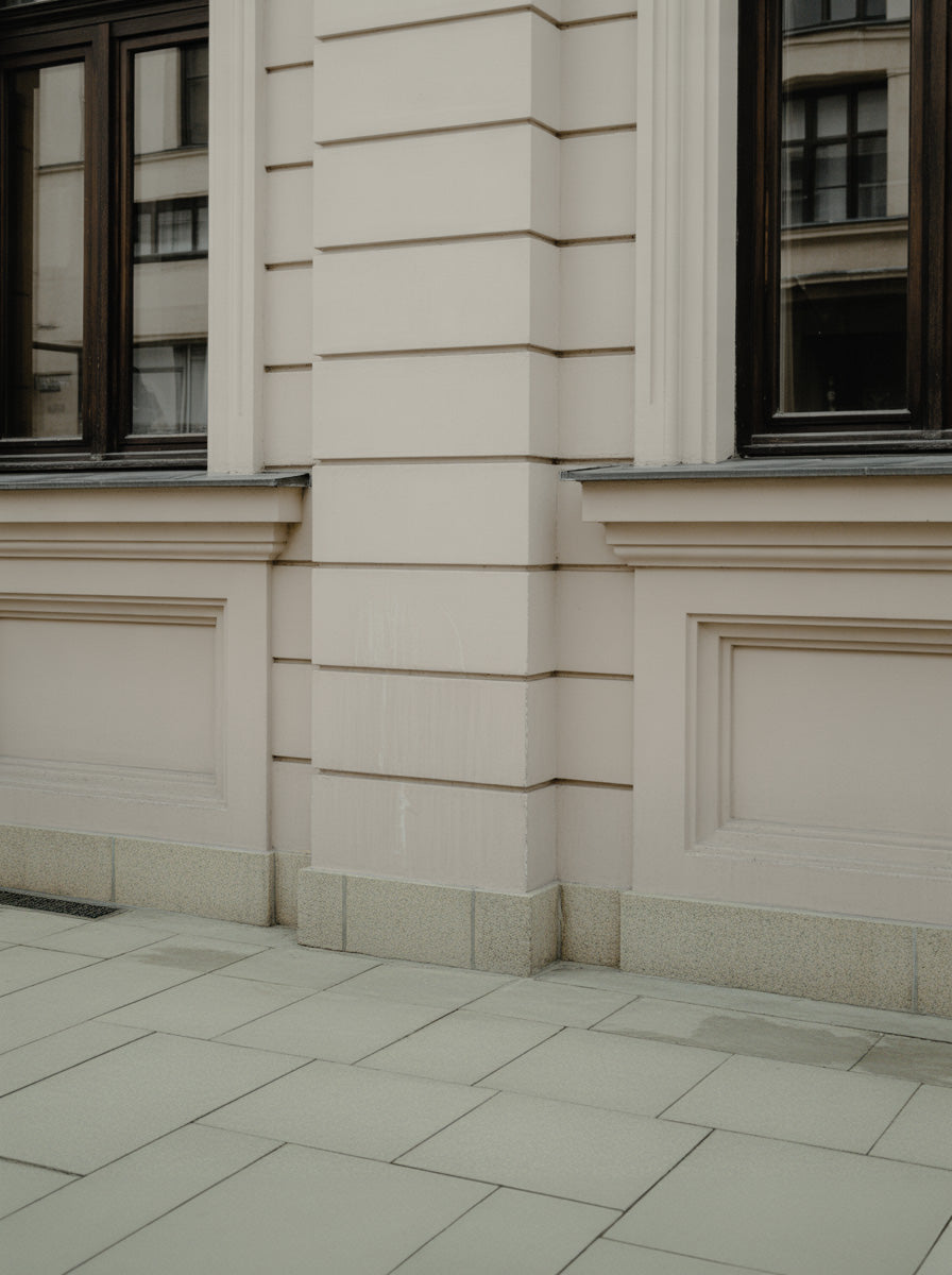 Classic stone building corner with layered masonry details and pale sidewalk paving