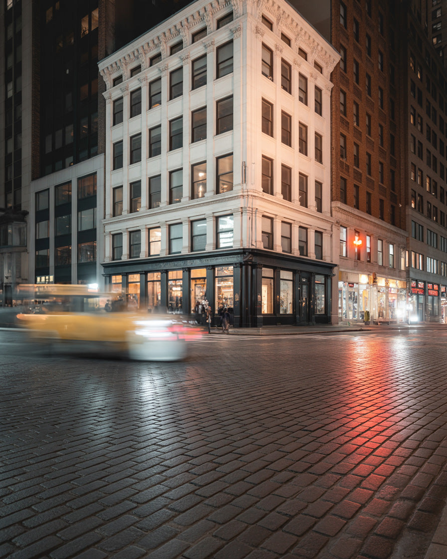 Historic city corner building at night with light trails