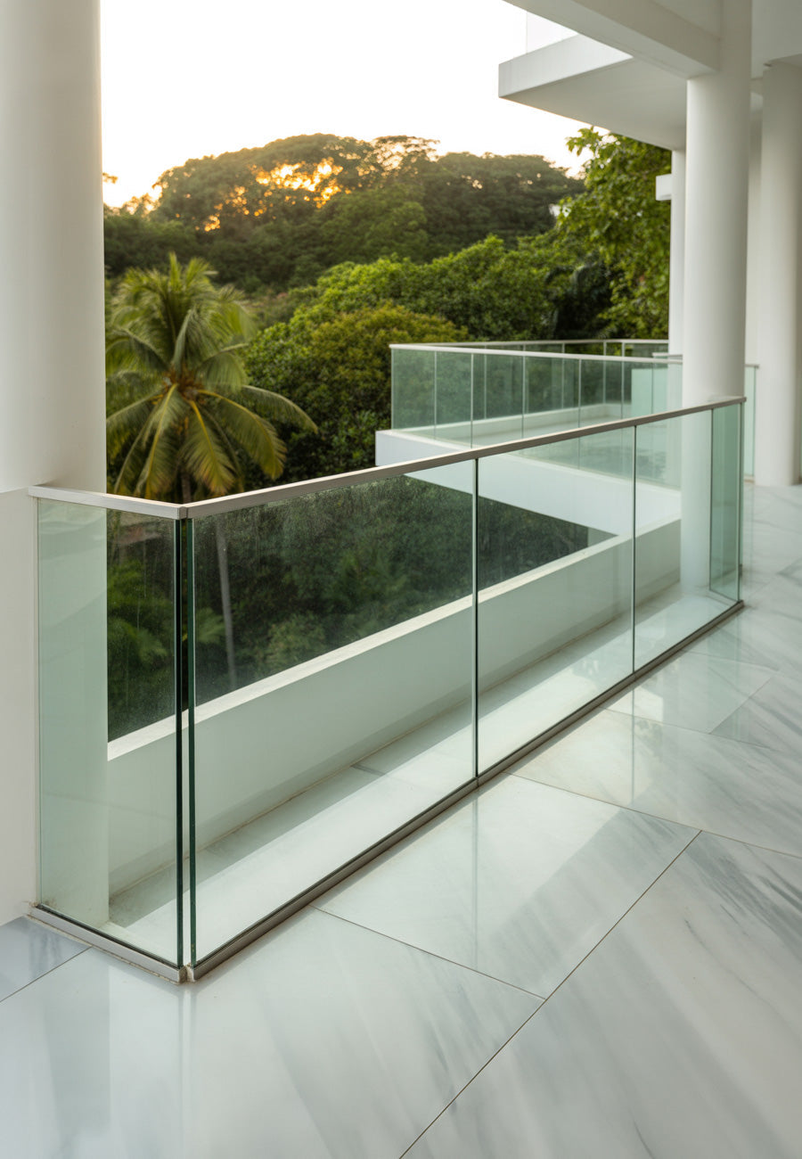 Modern white balcony with glass railings overlooking lush trees
