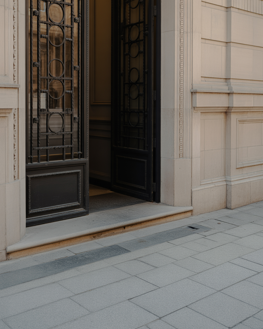 Ornate stone entrance with iron gate and sidewalk