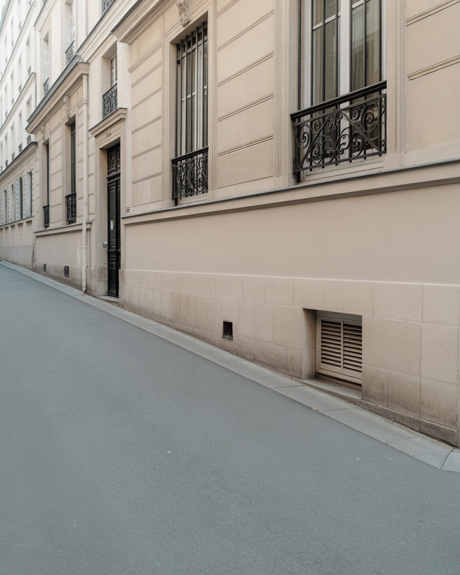 Long beige residential street facade with iron balconies and muted sidewalk