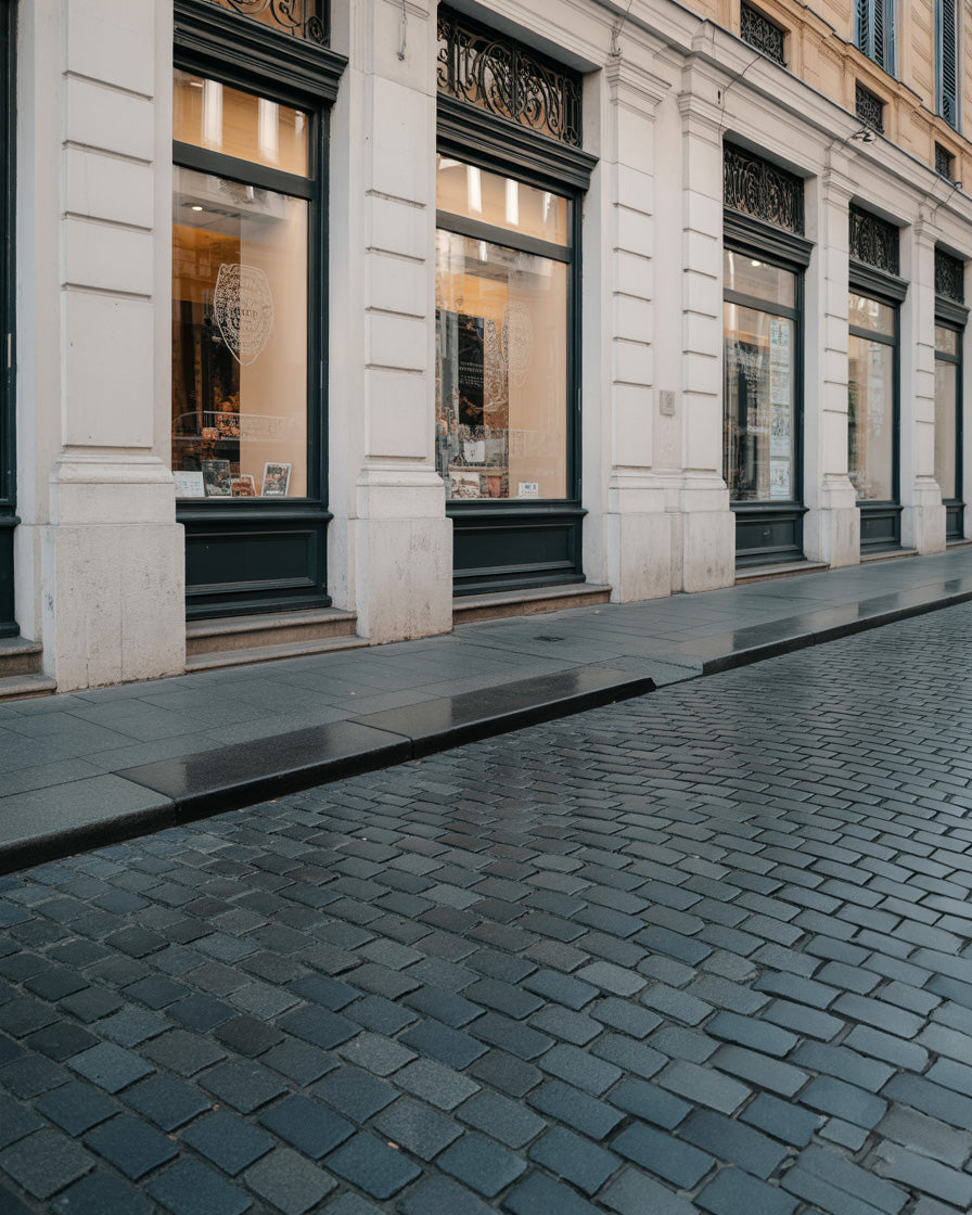 Refined city storefronts with classic facades and dark cobblestone street