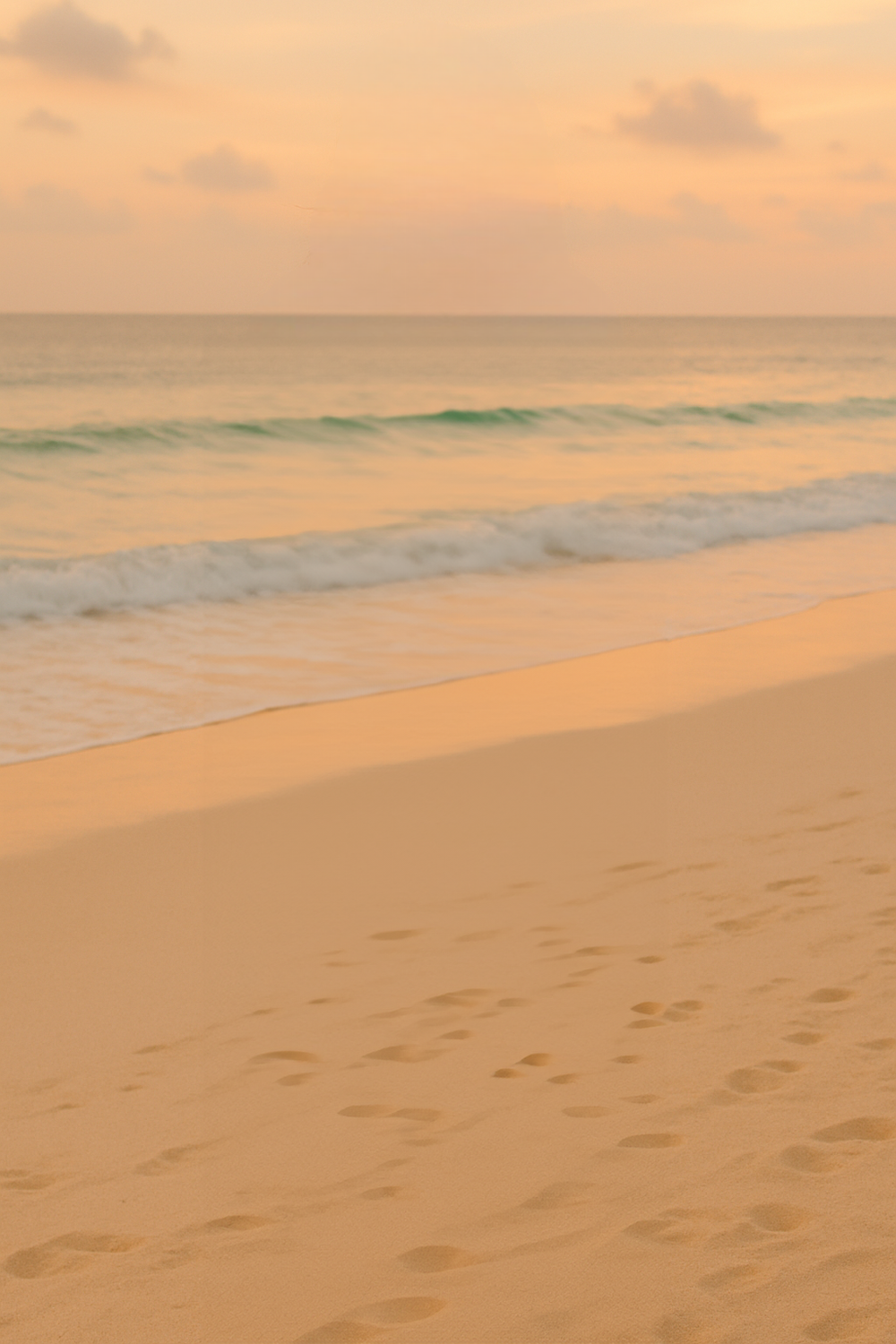 Golden hour beach shoreline with soft waves and clouds