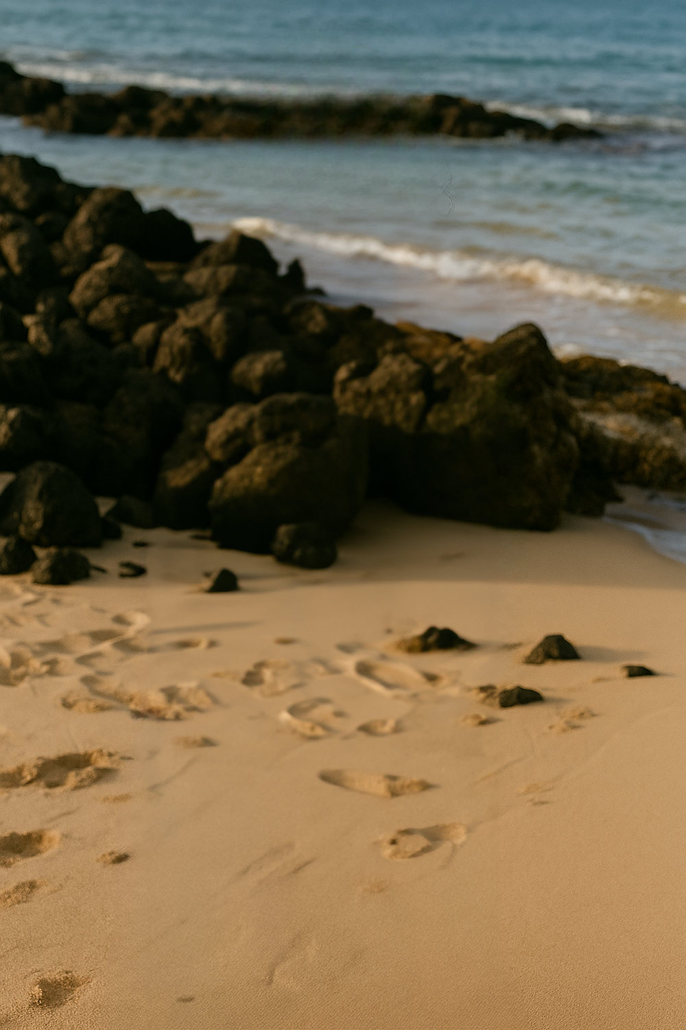 Golden sand beach with scattered black volcanic rock shoreline